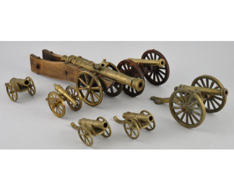 A cast brass model of a seventeenth Century cannon, on wood carriage, L. 35cm, together with six similar smaller examples (7)