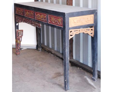 A Chinese ebonised and red and gilt lacquered side table, with a four panel carved foliate frieze, raised on square legs and 