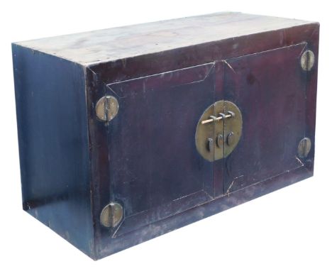 A Chinese hardwood cupboard, or trunk, with two doors and a circular central lock plate, 76cm high, 125cm wide, 59cm deep. 