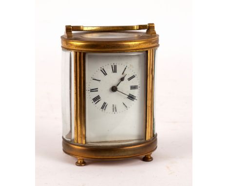 A carriage clock in an oval gilt brass case, 17cm high