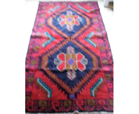 An Afghan wool Hearthi Balochi burgundy-ground hand knotted rug with multicoloured isometric designs, double border with shor