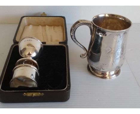 A George VI silver mug by H Phillips, London, 1946, 255g, inscribed and a cased silver napkin ring and egg cup by I S Greenbe