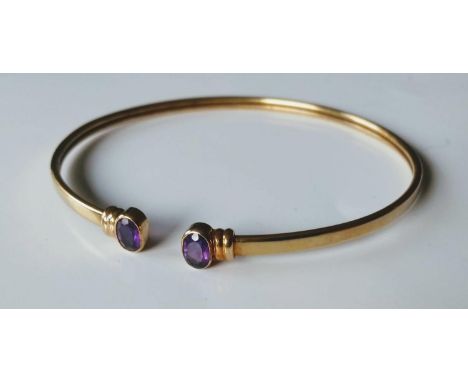 A 9ct yellow gold bangle with oval-cut amethyst decoration, hallmarked, 6g 