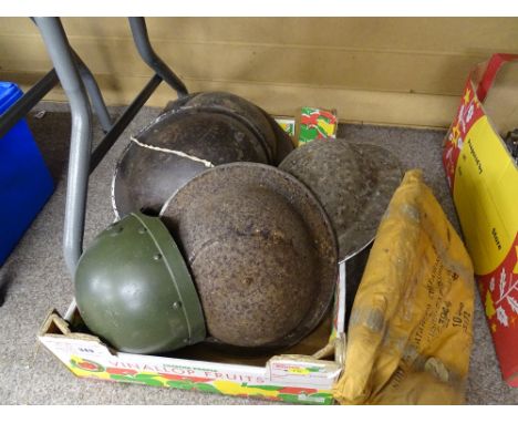 Four vintage military tin hats and one other along with a broad arrow marked inflatable exposure containing suit