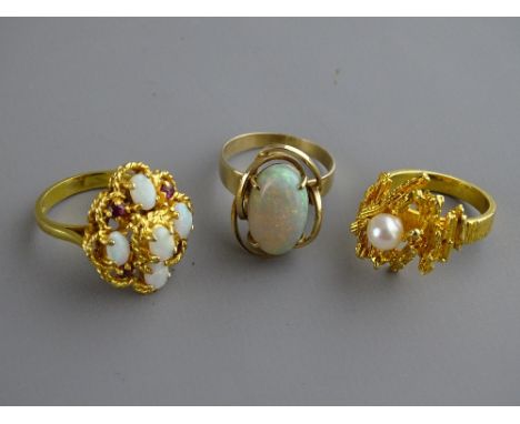 Three nine carat gold dress rings to include a single opal, size 'R', an opal and ruby cluster, size 'P' and a bark effect wi