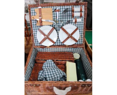 A wicker picnic hamper with contents