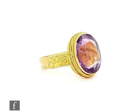 A 15ct single stone amethyst ring, oval stones within a beaded collar set border and foliate detail to wide shoulders, weight