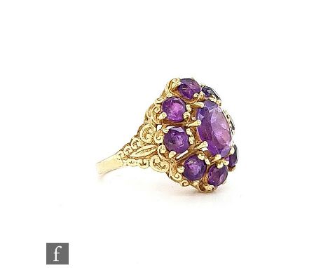 A modern 9ct hallmarked amethyst cluster ring, central oval claw set stone within an eight stone borders all to scroll detail