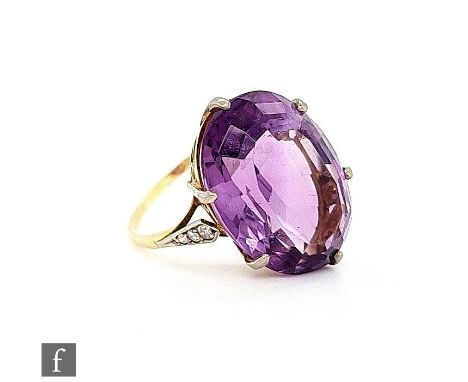 A 9ct amethyst ring, claw set oval stone, length 22mm, with three diamonds set to each shoulder, weight 8.8g, ring size T 1/2