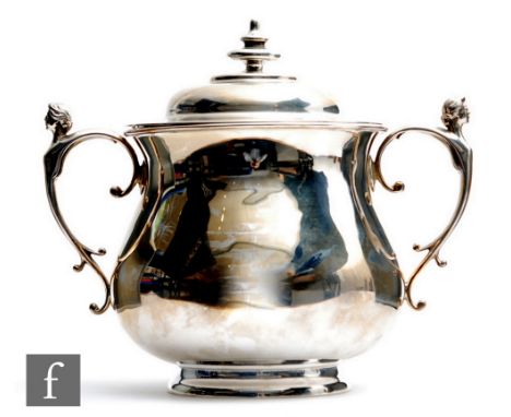 A hallmarked silver bowl and cover of plain baluster form terminating in twin scroll handles each with detailed with a female