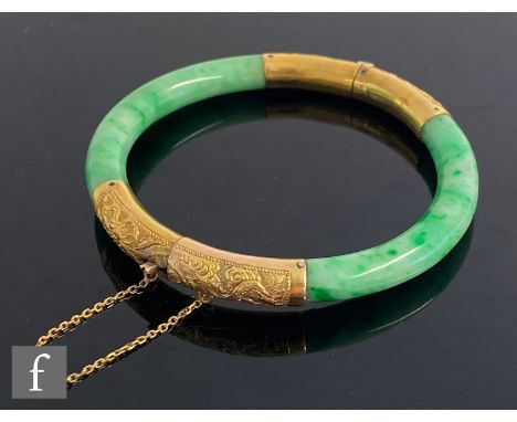 A mid 20th Century 15ct mounted nephrite hinged bangle with engraved dragon and bamboo leaves to the gold mounts, total weigh