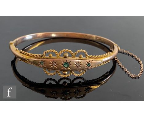 An early 20th Century 9ct hallmarked green garnet and diamond set hinged bangle, five alternate stones within a rope twist bo