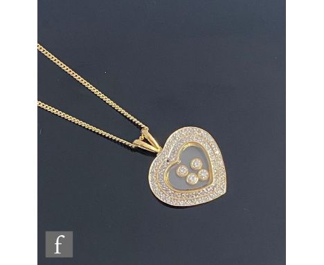 An 18ct hallmarked heart shaped happy diamond style pendant with four central diamonds to a clear glass panel within a border