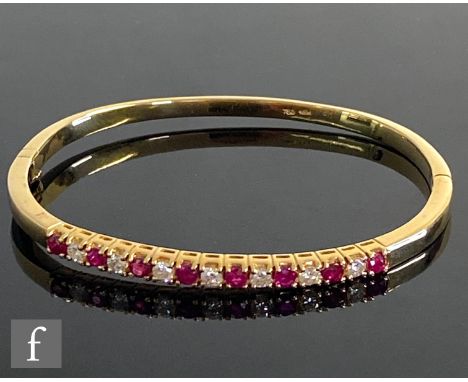 An 18ct ruby and diamond hinged bangle of plain form comprising fifteen alternating claw set stones, weight 14.5g, internal d
