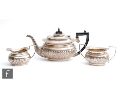 A hallmarked silver boat shaped three piece tea set with part fluted decoration, presentation engraving to base of teapot, to