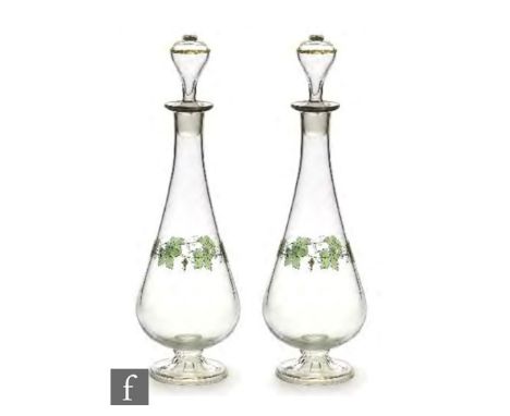 A pair of 1930s Czechoslovakian glass decanters, each of footed tapering form, the clear body enamel decorated with a band of