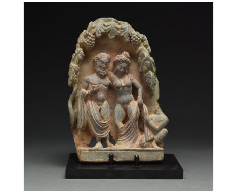 100 – 300 AD. Gandharan. A rare Gandharan yellowish-grey schist panel depicting a drunken Hercules embracing a female compani