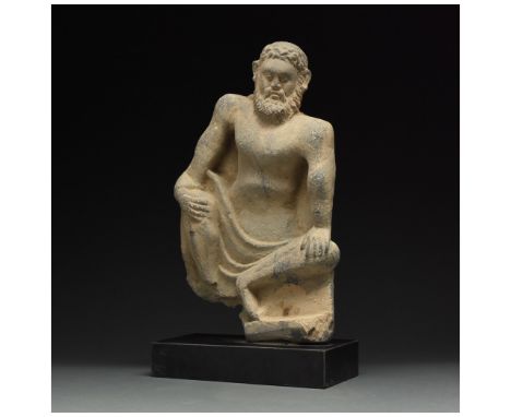 100 – 300 AD. Gandharan. A rare grey schist figure of Atlas in a crouching position, with his hands braced against his knees,