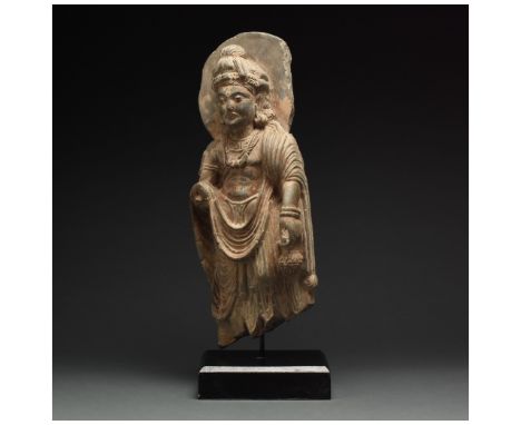 100 – 300 AD. Gandharan. A majestic schist standing buddha figure. The figure, bare-chested, wears an elaborate robe about hi