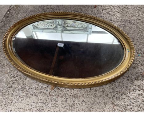 AN OVAL GILT FRAMED BEVEL EDGED WALL MIRROR 