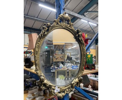 A VINTAGE GILT FRAMED OVAL MIRROR WITH CHERUB DECORATION, 43CM X 68CM 