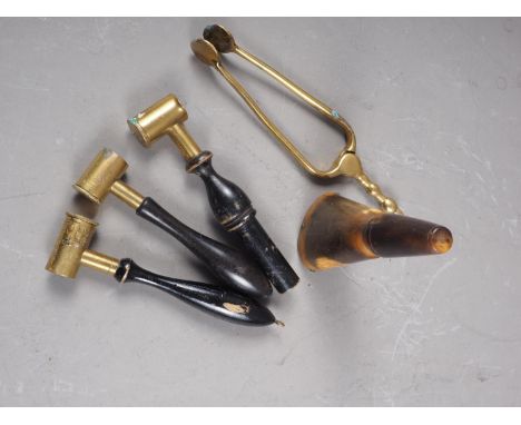 Three brass shot measures with ebonised handles, a pair of brass ember tongs and a horn powder flask 