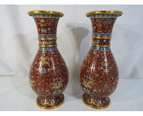 A pair of cloisonne vases of baluster form with scrolling floral and foliate decoration on a burnt red ground, blue counter e