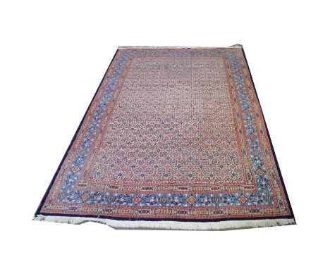 Persian carpet, the field filled with flowerheads against a cream ground, enclosed by foliate blue ground border, 330x220cm.