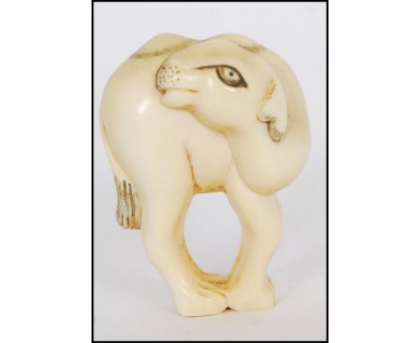 A rare Meiji period ivory Netsuke of a Bactrian camel. The head of the camel turned back standing on four feet. Signed to rea