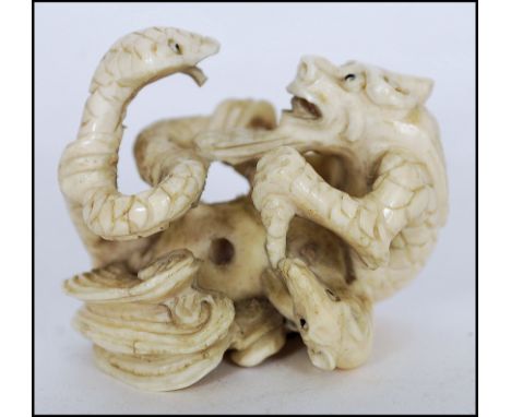 A rare Meiji period ivory Netsuke of a large dragon fighting with a snake and a rat. Signed well to the base. Measures 4cms t