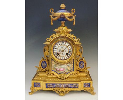 A Victorian ormolu mantel clock, the top with jeweled and gilt blue porcelain two handled urn with fruit finial and floral dr