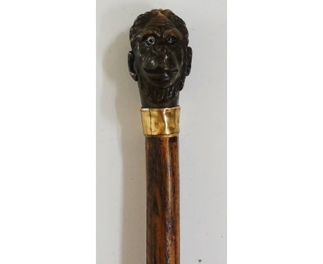 A late 19th / early 20th Century walking stick, the horn handle carved as a monkey's head, gilt brass bevelled collar, beech?