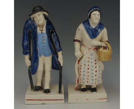 A pair of Staffordshire polychrome decorated pottery figures, one an invalid on pair of crutches, wearing long blue coat and 