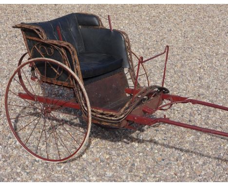 A small two wheeled pony trap, the burgundy painted metal and wooden frame with woven rim, faux leather button backed seat, m