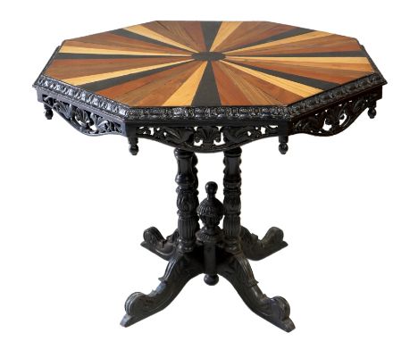 An Anglo-Indian octagonal centre table, the segmental coloured wood top centred on an ebony octagonal panel with foliate carv