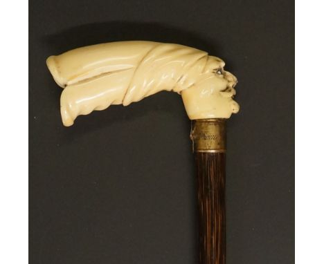 An Edwardian walking stick, the ivory handle carved with head of an Arab, gilt brass collar engraved MW from Jim and Nelly 19