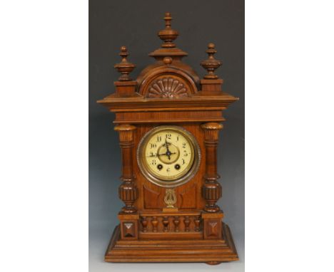 A late 19th Century German musical mantel clock, the walnut case with domed top, three compressed urn and spire finials and c