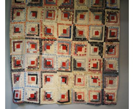 An early to mid 20th Century log cabin patchwork quilt made up of seven by ten multi coloured squares, each with central red 