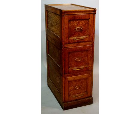 An oak three drawer panelled filing cabinet with gold painted iron mounts, 36cm wide, 115cm high, Circa 1920