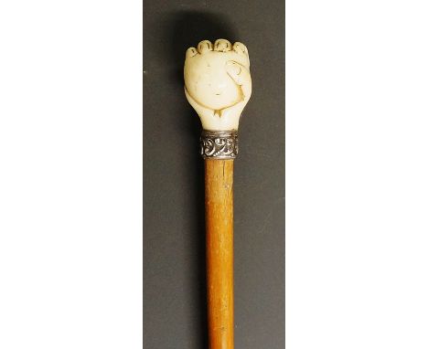 A Victorian walking stick with carved ivory terminal in the form of a hand clasping an orb, the silver coloured metal collar 