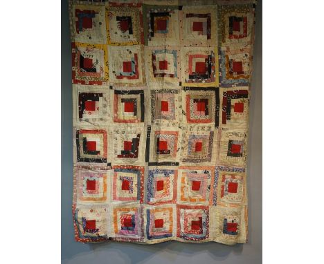 An early to mid 20th Century log cabin patchwork quilt made up of ten by nine multi coloured squares, each with central red p