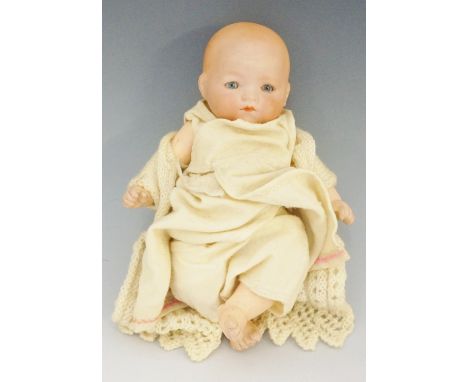 A small Armand Marseille porcelain headed doll with closing eyes, composite body and articulated limbs, clothed in hand made 