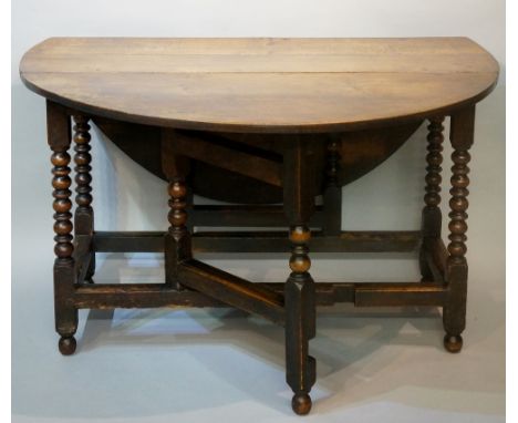 An oak gate leg table, the oval top above single frieze drawer on bobbin turned supports joined by moulded stretchers, turned