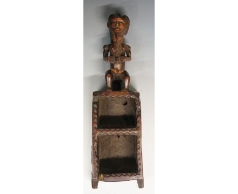 A tribal carved shelf or box surmounted by a female figure, above two open shelves with rudimentary dogtooth carved sides, ca