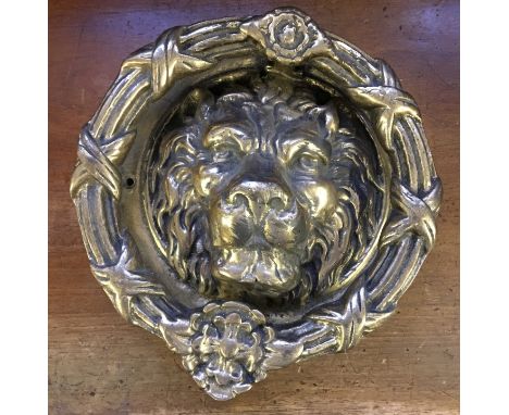 A brass door knocker with lion mask design.