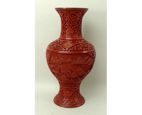 A cinnabar baluster lacquer vase, carved with landscape panels, with blue enamel on brass in the interior and on the base, 23