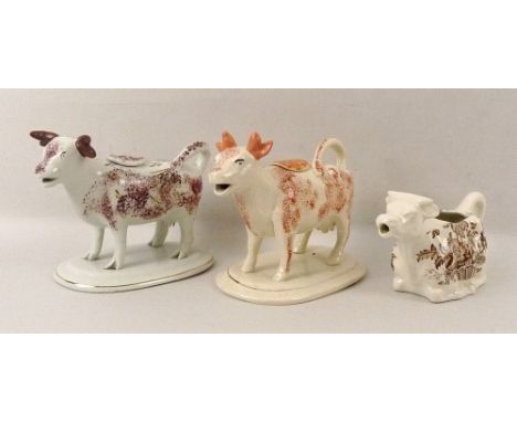 A group of three Staffordshire cow creamers, comprising a creamer on oval stand with terracotta blush decoration and gilded h