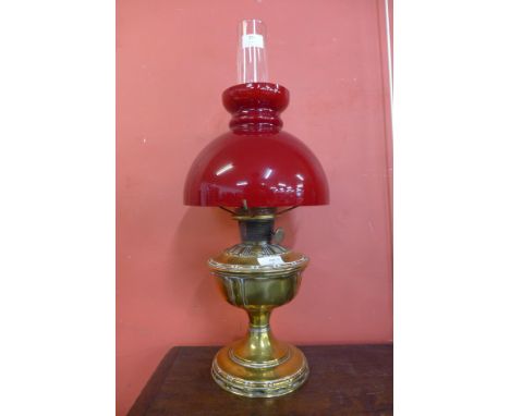 A Victorian brass oil lamp with red glass shade ( converted to electric) 