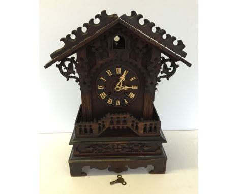 A large antique Black Forest mantle cuckoo clock with carved & fretwork decoration, 56cm tall. In working condition but needs
