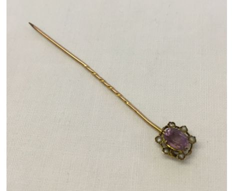 A Victorian gold stick pin set with central amethyst and 6 seed pearls (tests as 15ct).